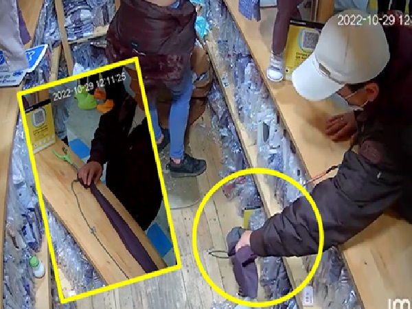 "With clamp picks up objects", thief grabs and takes cell phones and other objects in clothing stores
